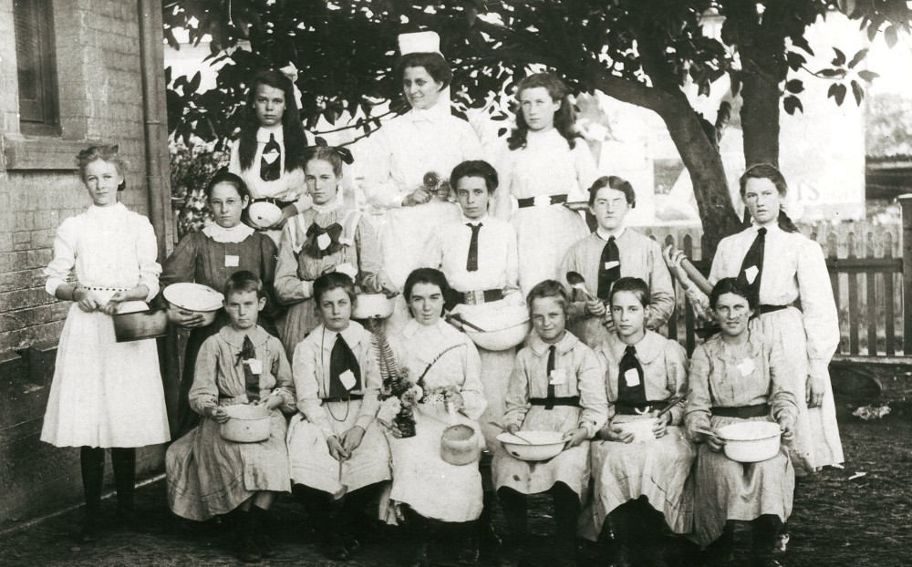 Cooking classes in public schools were established in 1897. This group shows girls holding basins, pots, spoons and what may be a rolling pin. The teacher is wearing apron and cap. Burwood Public School Cookery Class, 1908. Digital ID 15051_a047_002139 Cooking classes in public schools were established in 1897. This group shows girls holding basins, pots, spoons and what may be a rolling pin. The teacher is wearing apron and cap. Burwood Public School Cookery Class, 1908. Digital ID 15051_a047_002139